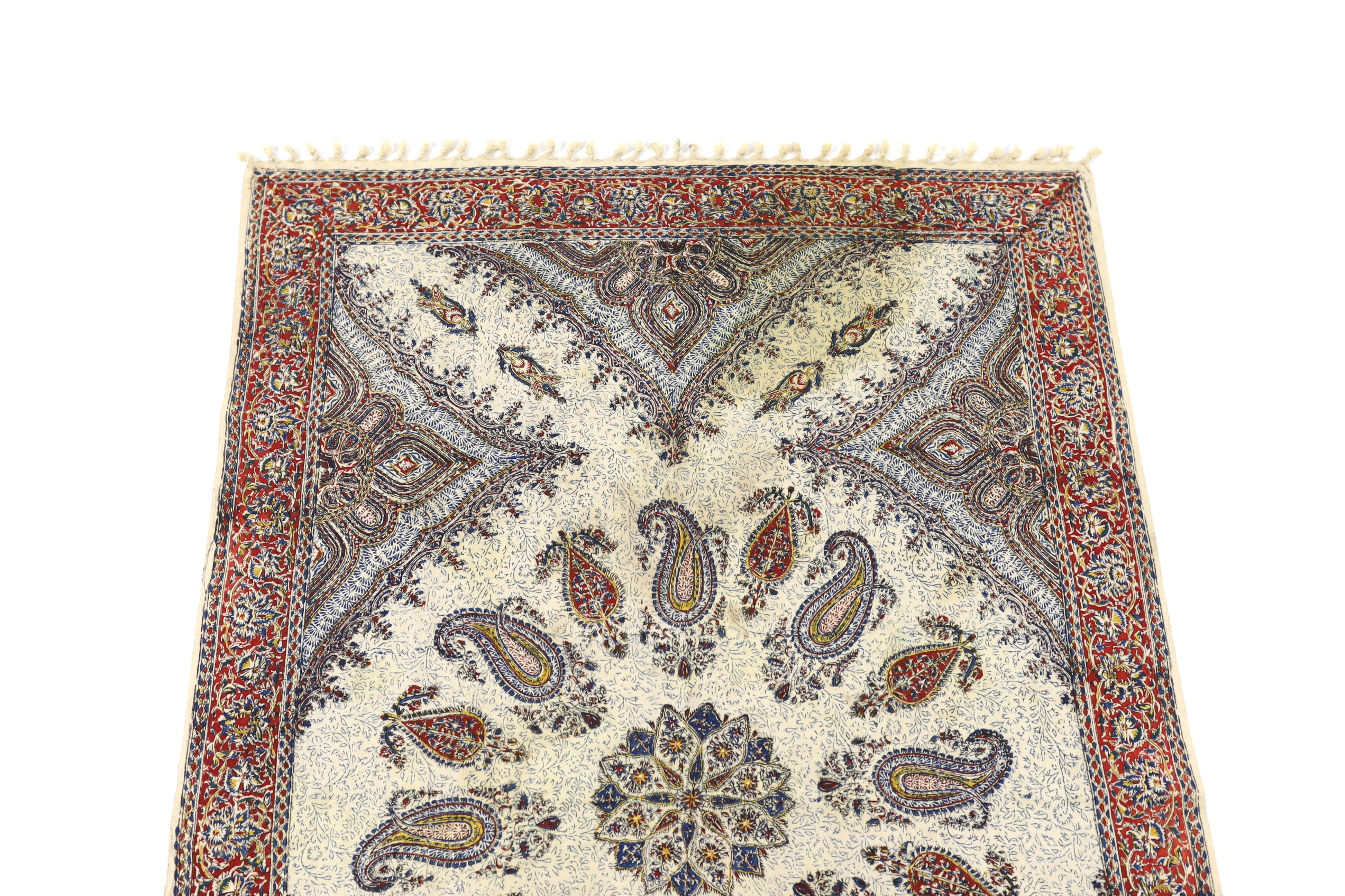 A 20th century Iranian printed paisley shawl, designed using indigo, red and ochre dyes, finished with knotted tassels either end, with an ink maker’s stamp on reverse, 148cm long x 100cm wide